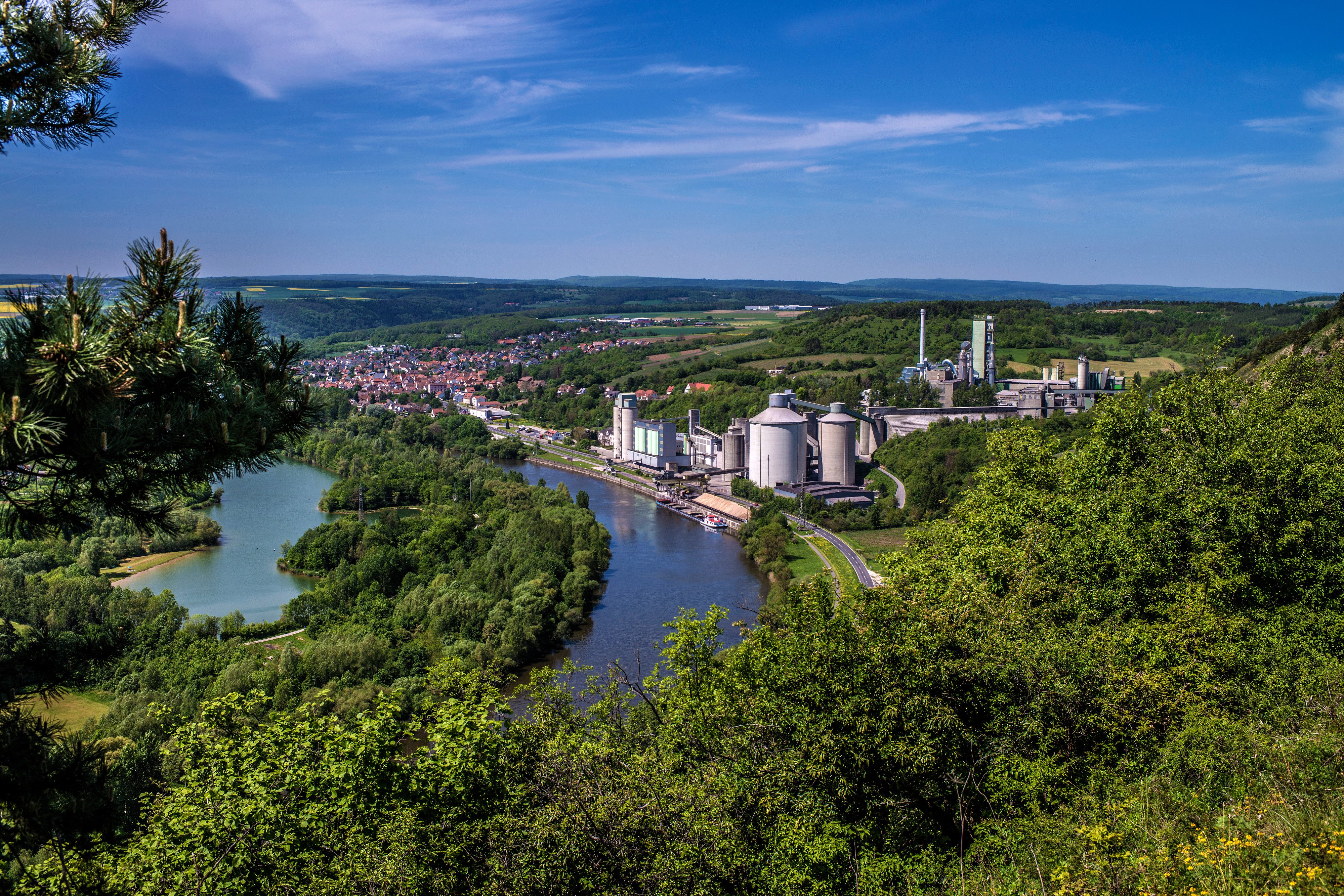 View from a hill to a cement plant in the countryside next to a body of water