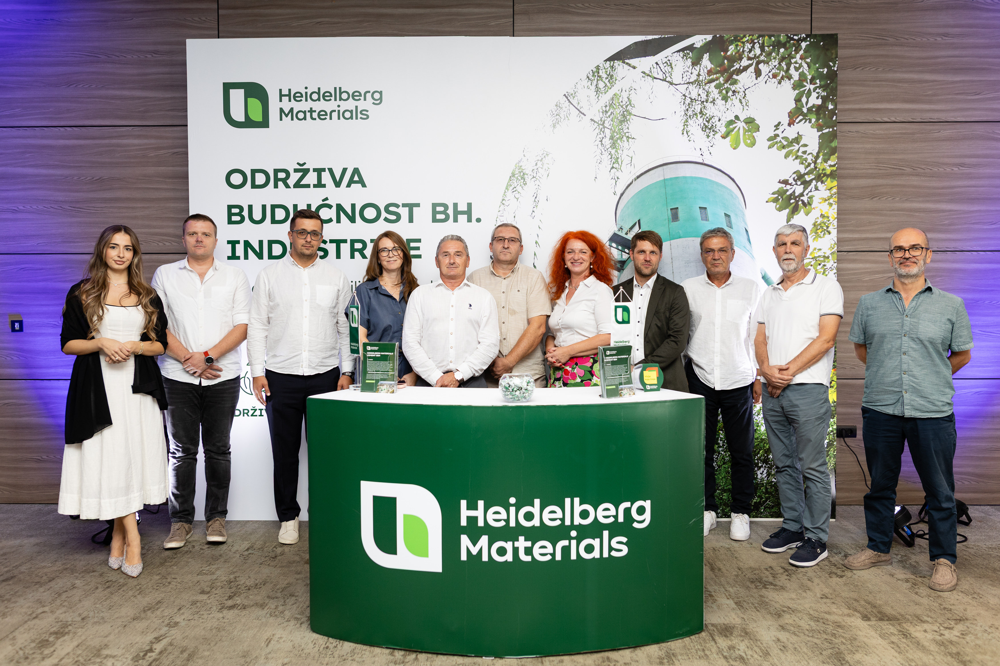 Grupa ljudi stoji ispred štanda sa logotipom Heidelberg Materials, uz poruku o održivoj budućnosti industrije u BiH.
